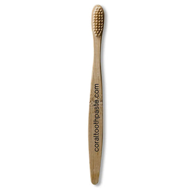 Bamboo toothbrush with coral toothpaste.com branding on a white background