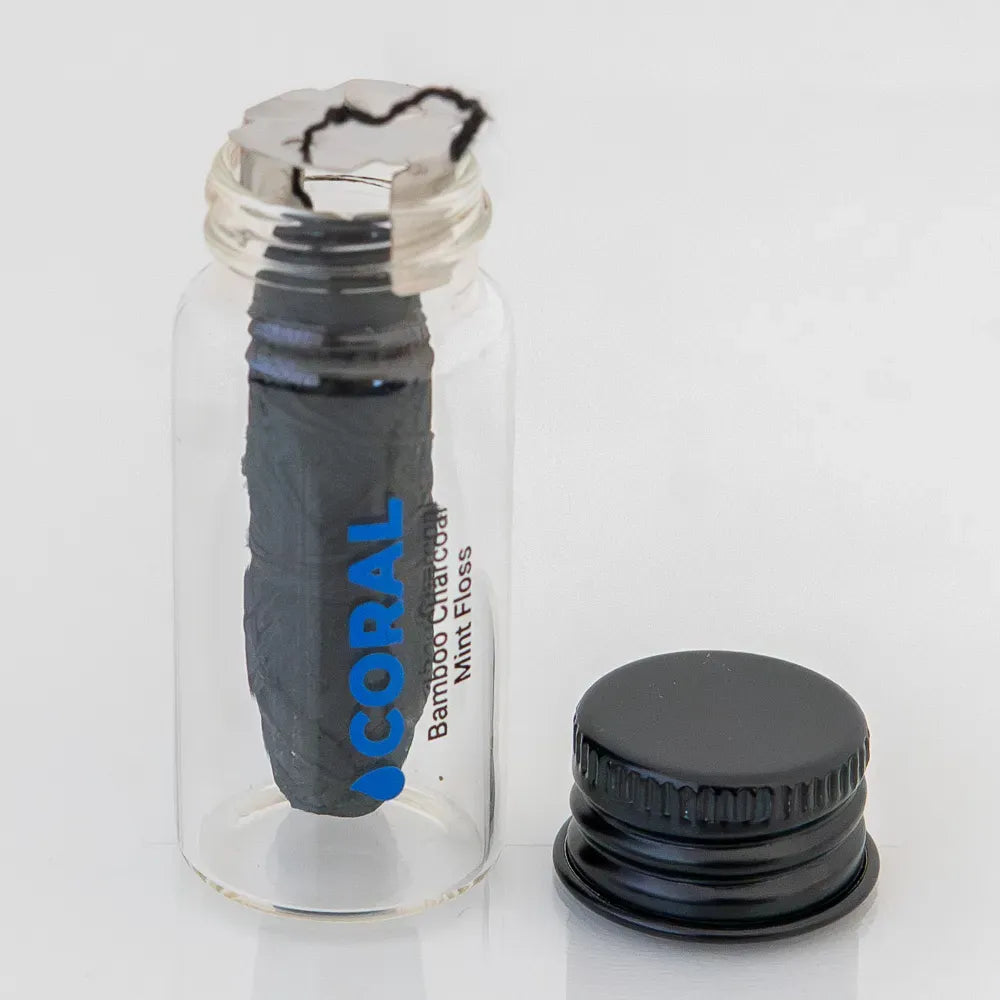 Coral Bamboo Charcoal Mint Floss in eco-friendly glass jar with open black lid, showing biodegradable bamboo charcoal dental floss for natural and sustainable oral care.
