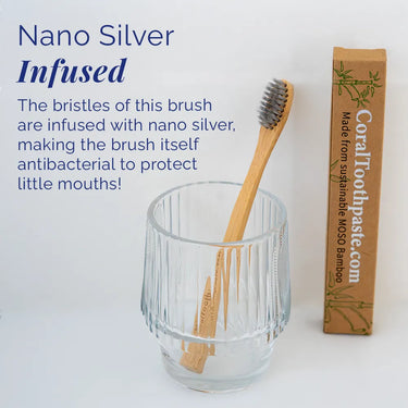 Coral Kids Bamboo Toothbrush with nano silver–infused bristles shown in a glass cup beside sustainable MOSO bamboo packaging, designed to provide gentle antibacterial cleaning and protect little mouths during daily brushing.