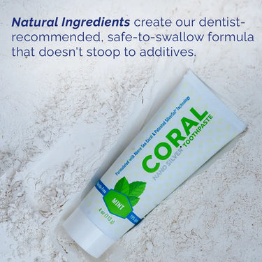 Coral toothpaste tube on a textured surface with text about natural ingredients.