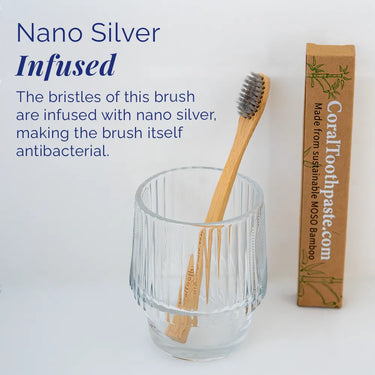 All-natural bamboo toothbrush with nano silver–infused bristles, shown in a glass holder with sustainable MOSO bamboo packaging, designed for antibacterial oral care